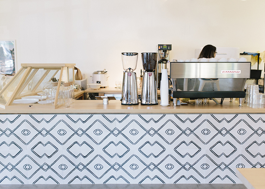 A wide shot of the entire coffee bar, and pastry case showcasing the butcher block counter and abstract tiles